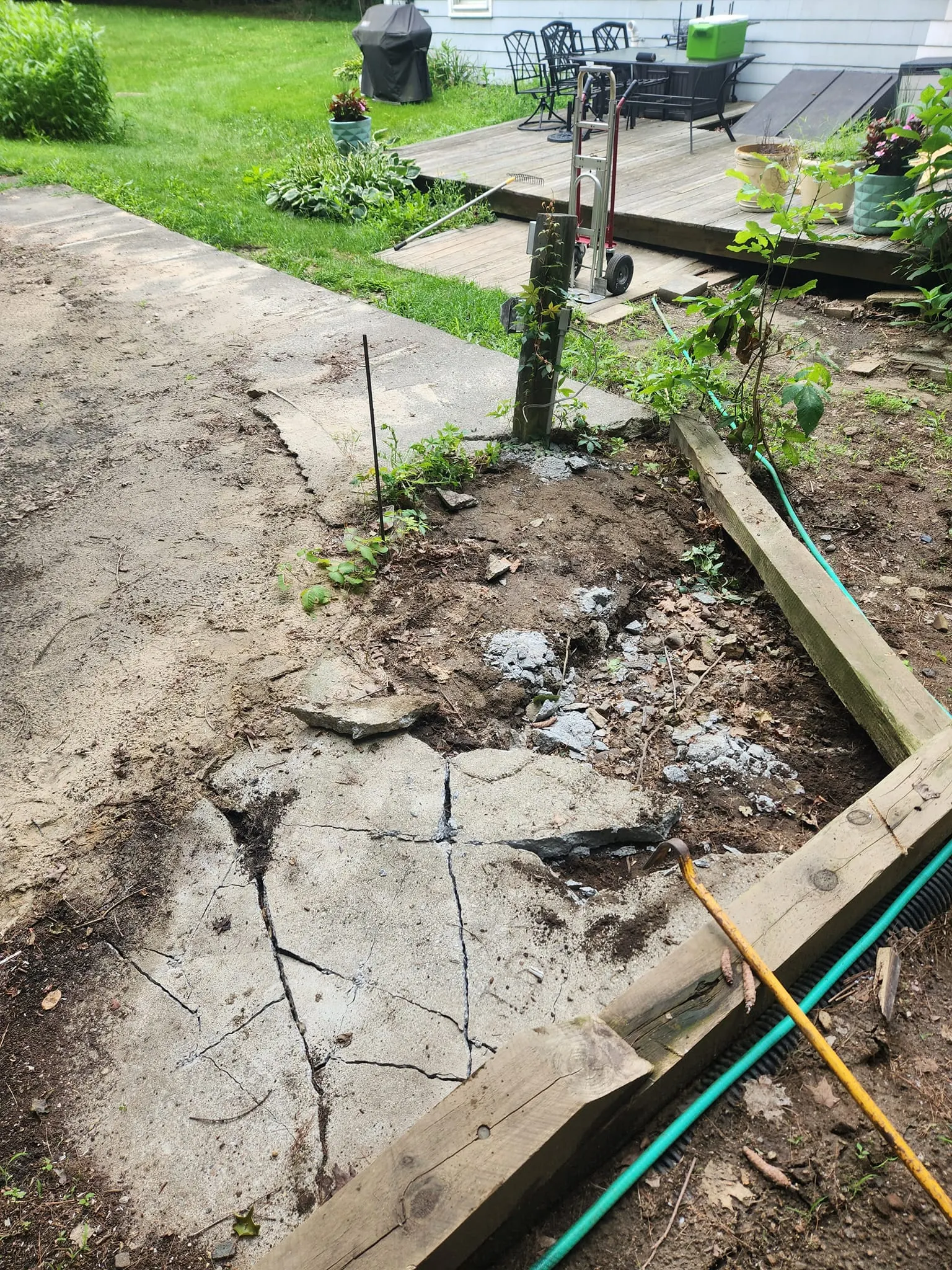 Broken-up concrete walkway and landscape timbers ready for debris removal